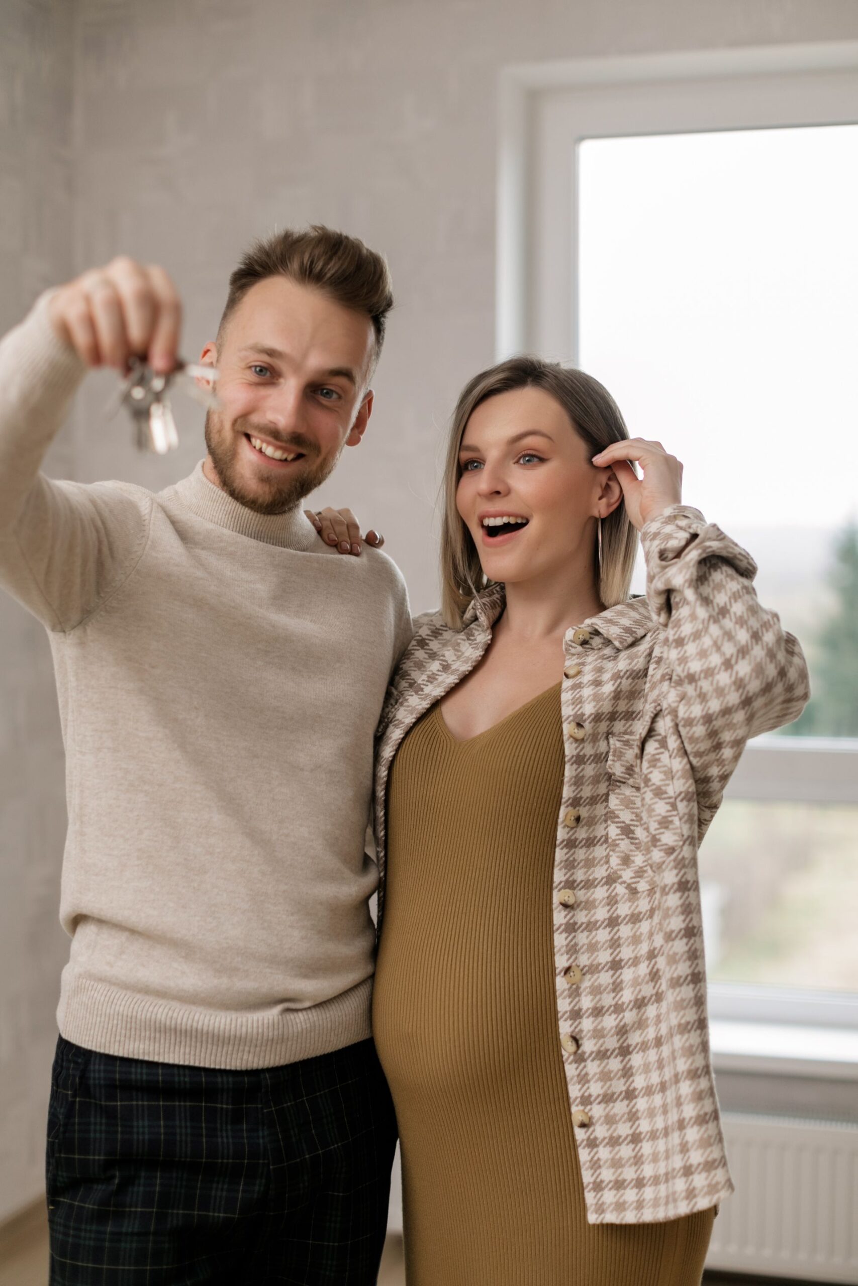 Pareja joven sonriente sosteniendo las llaves de su nueva vivienda